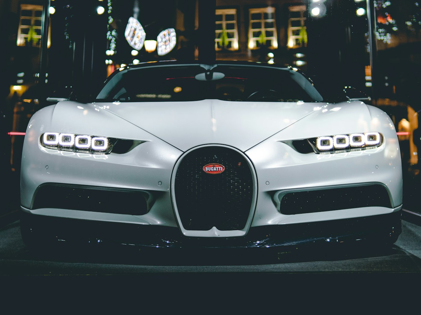 Frontal de un Bugatti Chiron blanco en una exhibición nocturna.