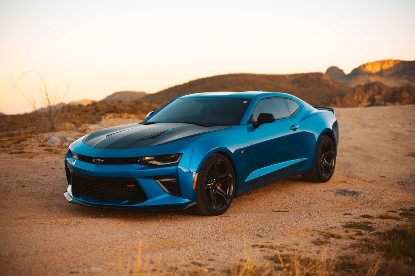 Chevrolet Camaro SS azul con franjas negras en un paisaje desértico.