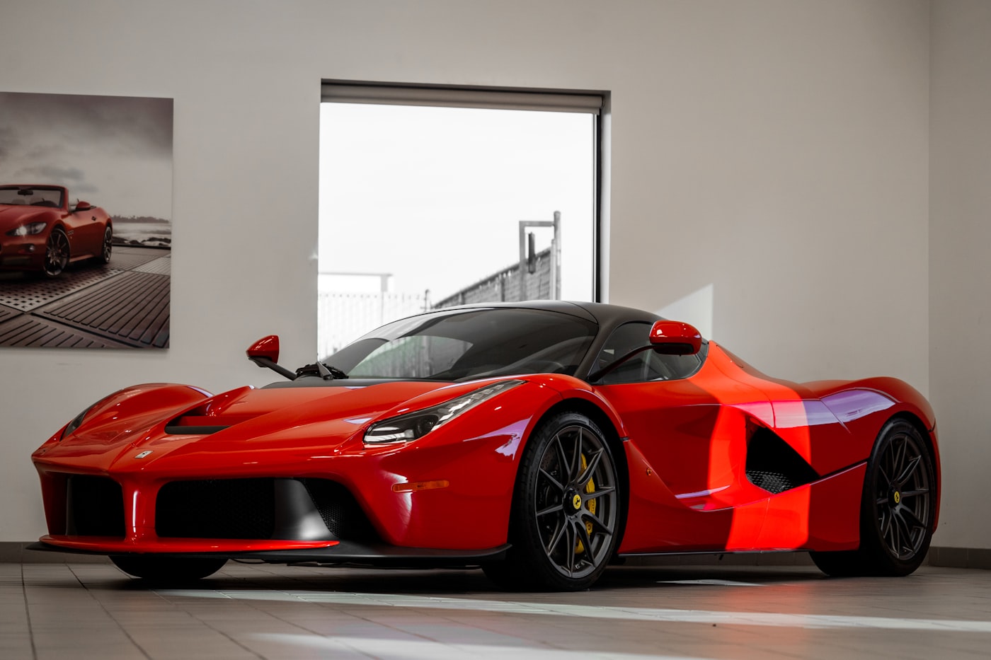 Ferrari LaFerrari rojo exhibido en un showroom de paredes blancas.