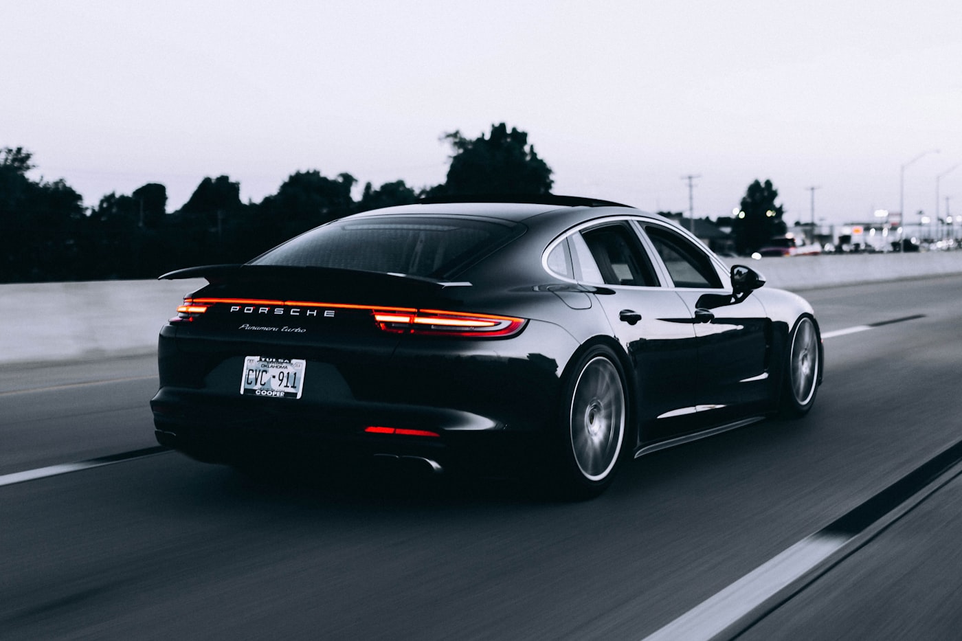 Porsche Panamera Turbo negro circulando por una autopista al atardecer.